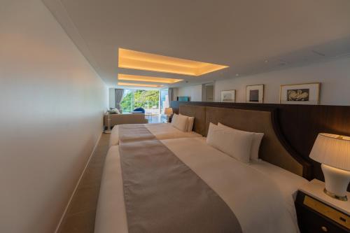 a hotel room with a large bed with white pillows at Hayama Hotel Otowa No Mori in Yokosuka
