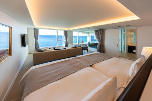 a bedroom with a large bed and a living room at Hayama Hotel Otowa No Mori in Yokosuka