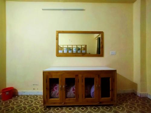 a wooden cabinet with a mirror on a wall at Orange sky home stay gadaGushaini near jibhi in Jibhi