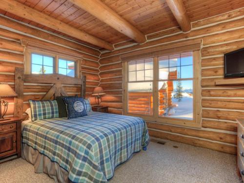 ein Schlafzimmer mit einem Bett in einem Blockhaus in der Unterkunft Powder Ridge Cabin Moose Ridge 5 in Gallatin Gateway