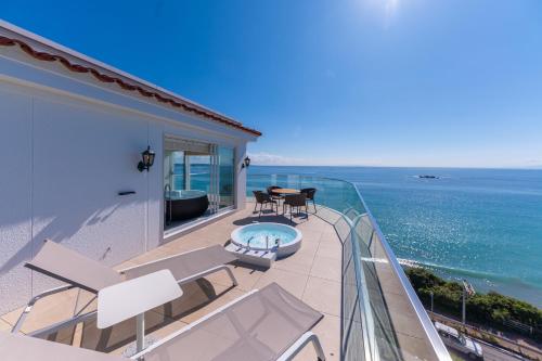 a balcony with a table and chairs and the ocean at Hayama Hotel Otowa No Mori in Yokosuka