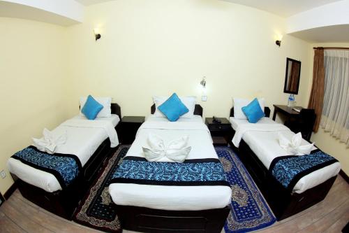 three beds in a room with blue pillows at Bag Packer's Lodge in Kathmandu