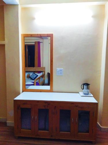 a bathroom with a mirror and a wooden cabinet at Orange sky home stay gadaGushaini near jibhi in Jibhi