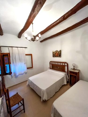 a bedroom with two beds and a chair in it at Casa Rural Nueva Araceli in Oliete