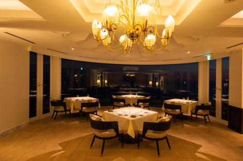 a dining room with tables and chairs and a chandelier at Hayama Hotel Otowa No Mori in Yokosuka