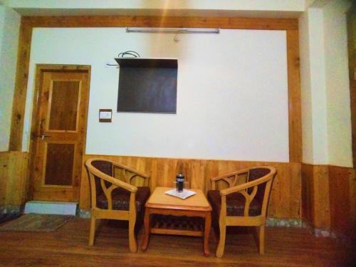a table and two chairs with a table and a screen at Orange sky home stay gadaGushaini near jibhi in Jibhi