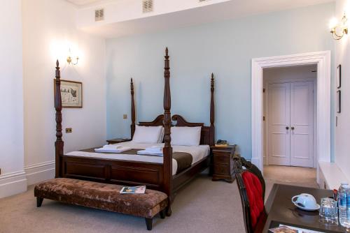 a bedroom with a bed and a table and a chair at Keppels Head Hotel in Portsmouth