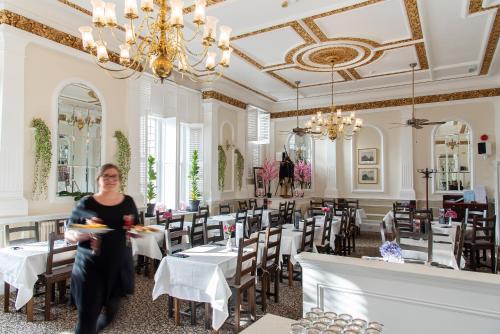 una mujer sentada en el comedor de un restaurante en Keppels Head Hotel, en Portsmouth