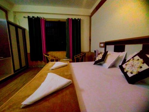 a bedroom with a large bed with white sheets and pillows at Orange sky home stay gadaGushaini near jibhi in Jibhi
