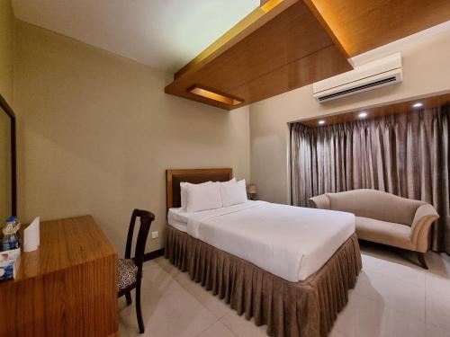 Pokój hotelowy z łóżkiem, krzesłem i biurkiem w obiekcie Hotel Fountain Luxury In Comfort w mieście Dhaka