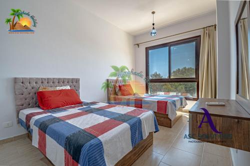 een slaapkamer met twee bedden en een raam bij Turtles Beach Resort Hurghada By VTGooo in Hurghada