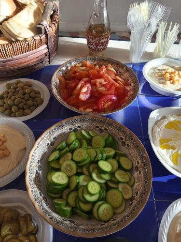 a table topped with bowls of food with cucumbers and tomatoes at BREAD HOUSE in Bethlehem