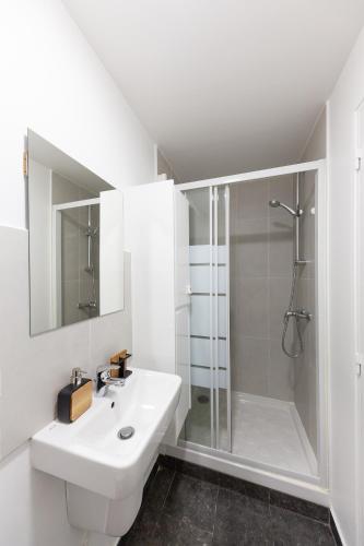 une salle de bain blanche avec une douche et un lavabo dans l'établissement Studio Cosy - proche Paris & Stade de France, à Pantin
