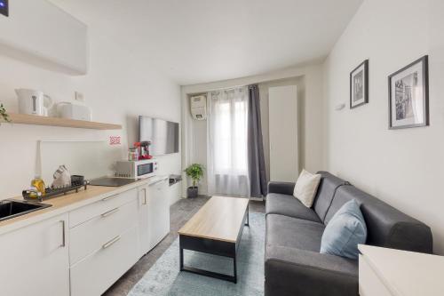 ein Wohnzimmer mit einem Sofa und einer Küche in der Unterkunft Studio Cosy - proche Paris & Stade de France in Pantin
