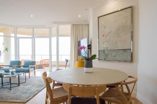 uma sala de estar com mesa e cadeiras em 801 Oyster Schelles - by Stay in Umhlanga em Durban