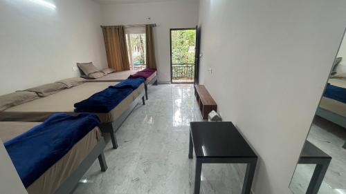 um quarto com três camas e uma mesa em Silver springs Homestay Chickmagalur em Chikmagalur