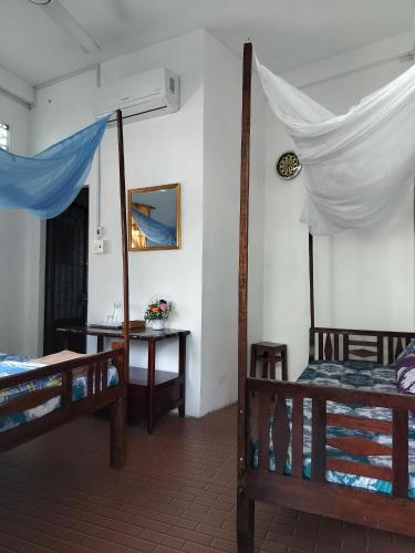 a room with two beds and a table and a desk at Happy Family Guesthouse in Vĩnh Long