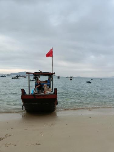 a boat on the beach with a red flag at Thanh Măng Hotel in Quang Ninh
