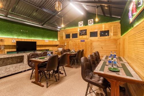 a dining room with tables and chairs and a television at Treebo Greenland, Mall Road in Shimla