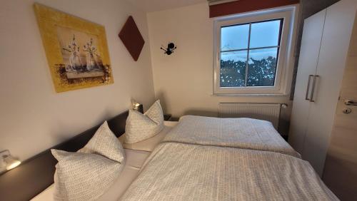 ein Schlafzimmer mit einem Bett mit Kissen und einem Fenster in der Unterkunft Ferienwohnung Gartentraum mit tollem Rasengarten in Ostseebad Karlshagen