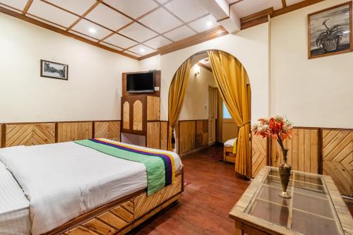 a bedroom with a bed and a table and a mirror at Treebo Greenland, Mall Road in Shimla