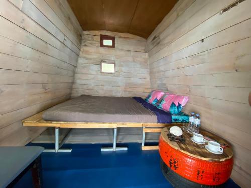 a bed in a wooden room with a wooden barrel at Homestay Hoa Núi in Cam Ranh