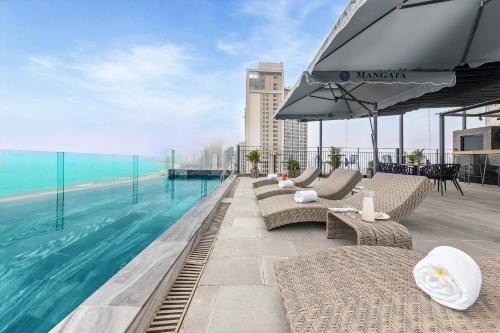 a swimming pool with chairs and an umbrella on a building at Mangata Beachfront Hotel in Da Nang