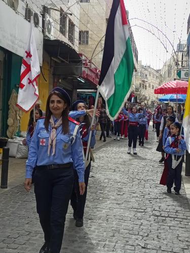 a woman walking down a street with flags at BREAD HOUSE in Bethlehem