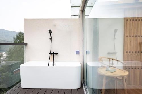 a bath tub in a bathroom with a table at Zhangjiajie Qiquan Vacation B&B in Zhangjiajie