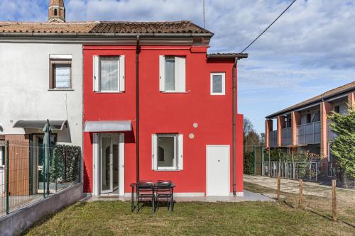 a red house with two chairs in front of it at 45 minutes to Venice - By Flora in Fagarè della Battaglia