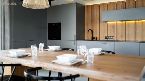 a dining room table with chairs and a kitchen at Wonder Home - Luksusowy dom Casa Moderna z dwoma tarasami w cichej okolicy blisko Karpacza in Kowary
