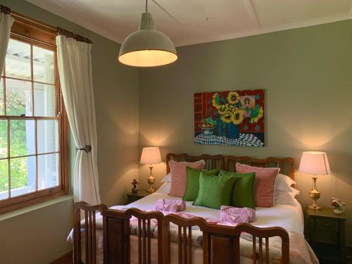 a bedroom with a bed with green and pink pillows at Rosehaven Cottage in Swellendam