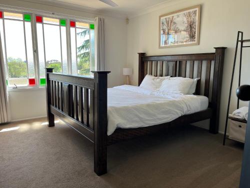 a bedroom with a wooden bed with white sheets and windows at Blue Willow Bathurst Country Getaway in Bathurst