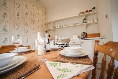 a dining room table with plates and wine glasses at Signal Point Cottage in Ventnor