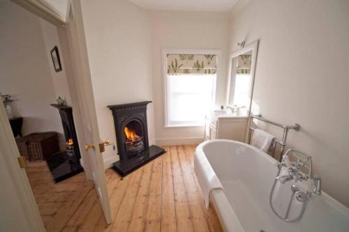 a bathroom with a bath tub and a fireplace at Signal Point Cottage in Ventnor