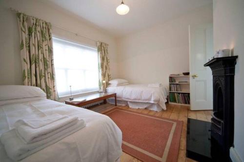 a bedroom with two beds and a window and a fireplace at Signal Point Cottage in Ventnor