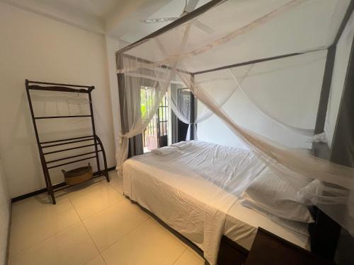 a bedroom with a canopy bed and a window at Tanzanite place in Tangalle