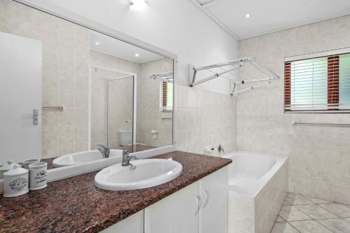 南布洛姆的住宿－San Lameer Villa 10902 - 4 Bedroom Superior - 8 pax - San Lameer Rental Agency，一间带水槽、浴缸和镜子的浴室