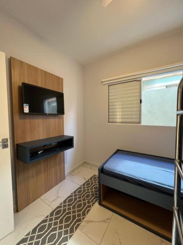 a bedroom with a bed and a flat screen tv at Casa de Campo Terra Preta in Mairiporã