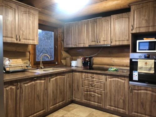 a kitchen with wooden cabinets and a sink and a microwave at Casa din Deal in Moldoveneşti