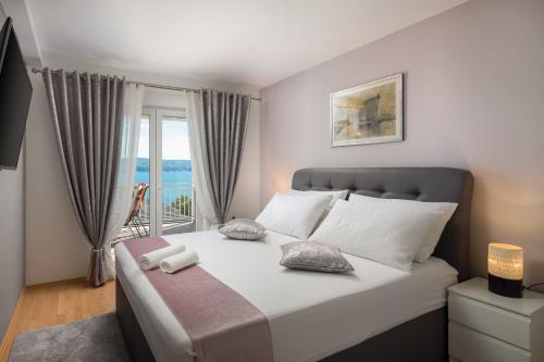 Un dormitorio con una cama grande con ventana. en Luxury Seafront Villa with Heated Pool, Jacuzzi, Sea View, 150 m from Beach, en Stanići