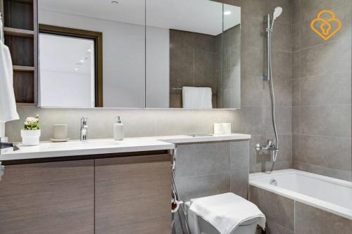 uma casa de banho com um lavatório, uma banheira e um espelho. em Keysplease Modern Luxury 1 BR Creek Harbour 2808 no Dubai