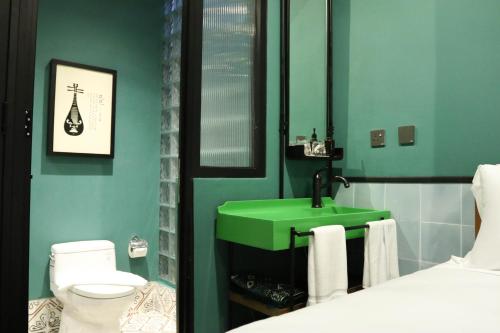 ein Badezimmer mit einem grünen Waschbecken und einem WC in der Unterkunft The Payang Hotel in Kuala Terengganu