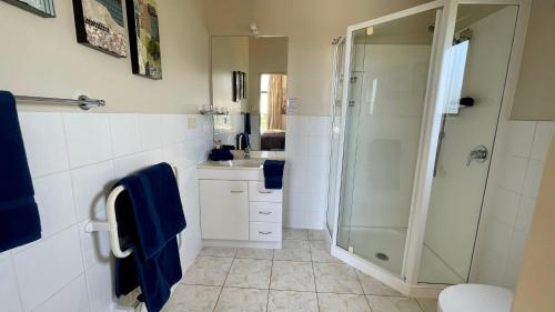 ein Bad mit einer Dusche und einem Waschbecken in der Unterkunft Oceans 8 - Mangawhai Heads Holiday Home in Mangawhai