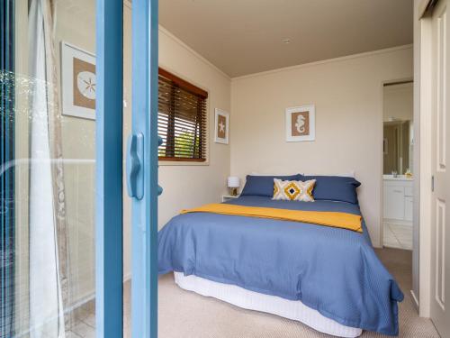 Schlafzimmer mit einem Bett mit blauer und gelber Bettwäsche in der Unterkunft Oceans 8 - Mangawhai Heads Holiday Home in Mangawhai