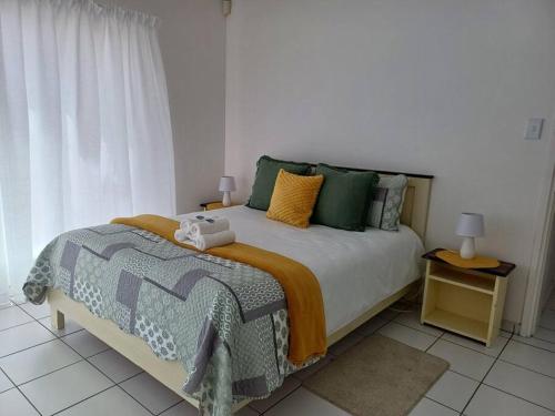 a bedroom with a bed with green and yellow pillows at House of Light in Swakopmund