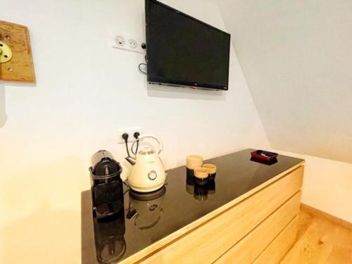 a room with a tv and a table with a tea kettle at Chambre Rose des Vents in Eguisheim