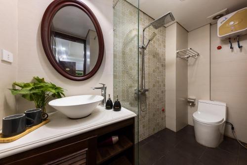 ein Badezimmer mit einem Waschbecken, einem WC und einem Spiegel in der Unterkunft Paddy Hotel in Hạ Long