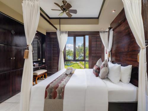 a bedroom with a large bed with a ceiling fan at Nirwana Resort Hotel in Lagoi