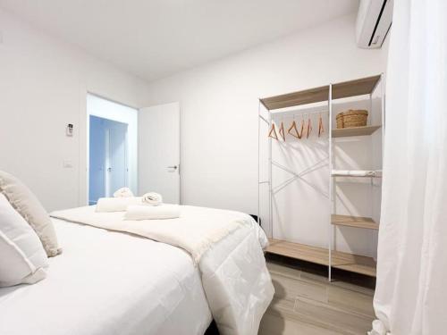 a white bedroom with two beds and a closet at Apartamentos Gredos 002 in Jaraiz de la Vera